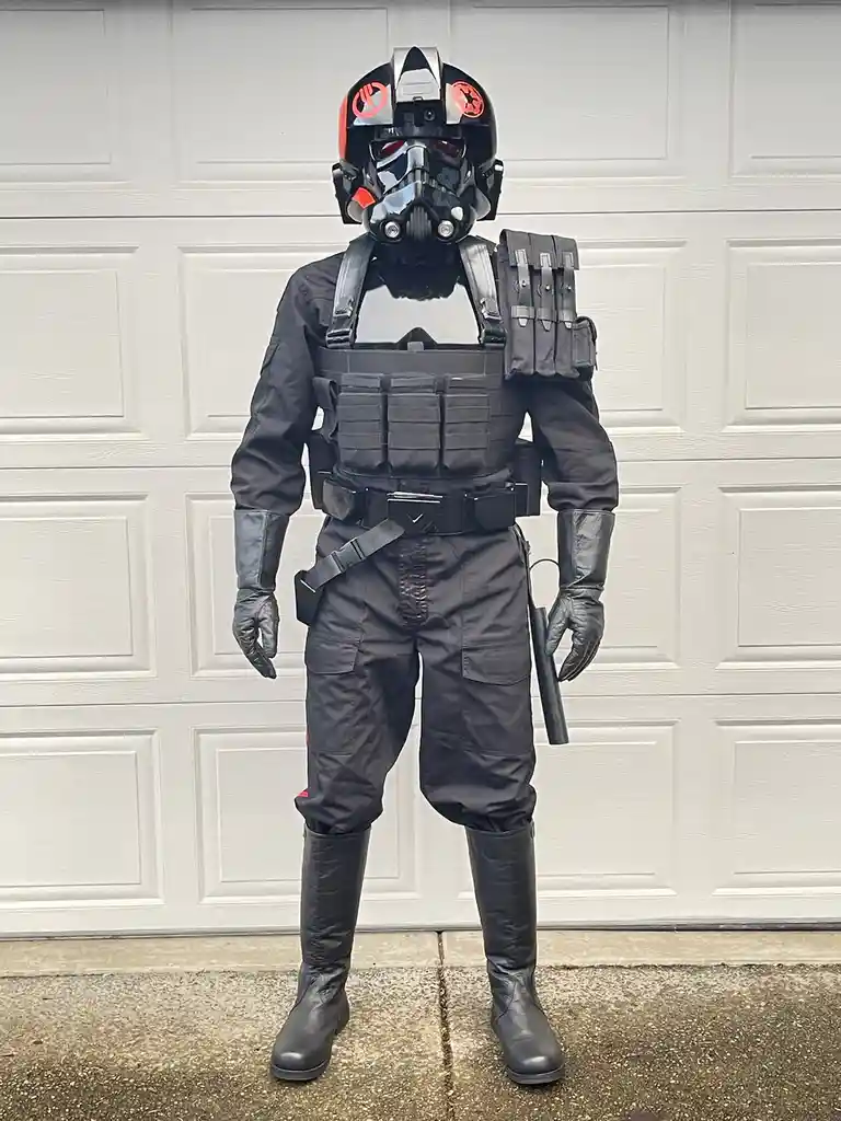 A person in a full-body Star Wars First Order Stormtrooper costume, including helmet with red markings, stands in front of a…
