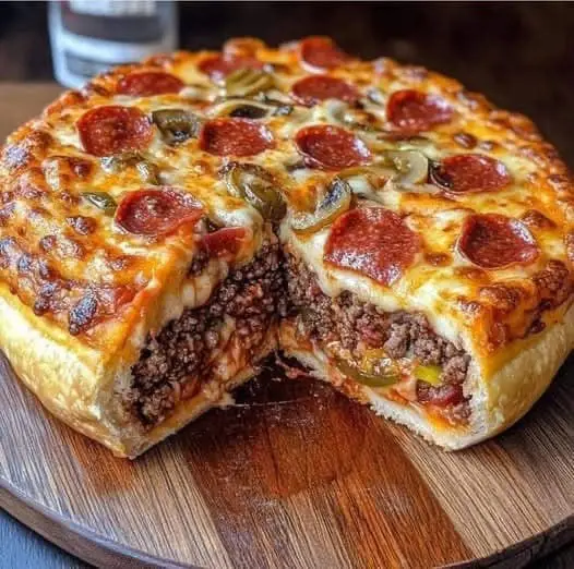 a close-up photo of a round, cheesy pizza with pepperoni and green olives on top, but a slice has been removed to reveal a…