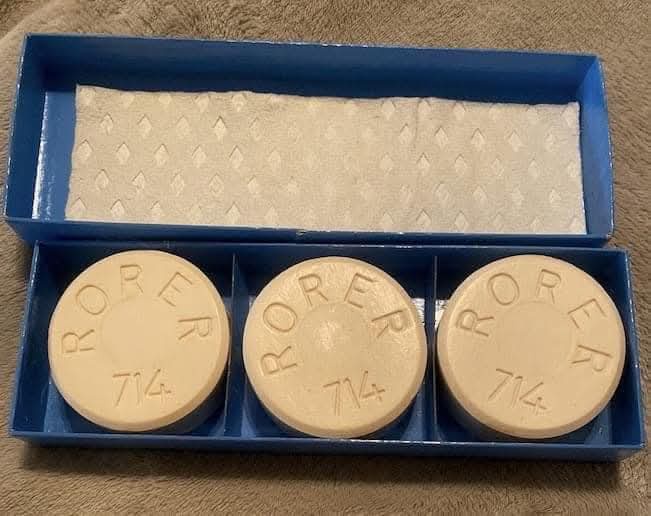 Three beige, round pills embossed with 'RORER 714' sit in a blue plastic tray. The lid of the tray, which is open, reveals a…