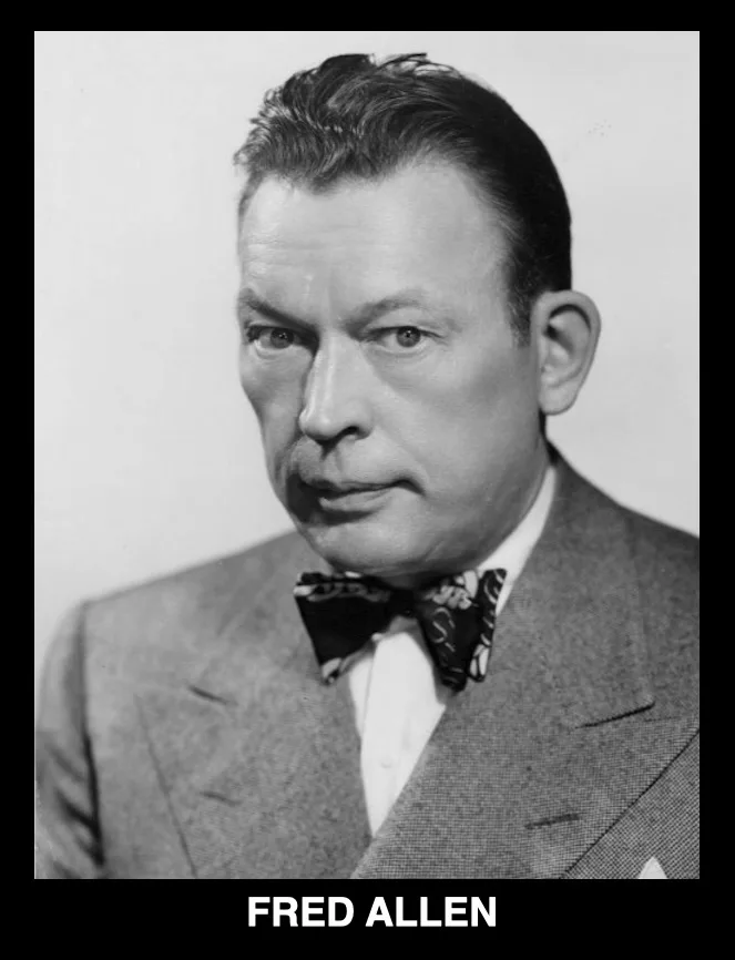 A black-and-white portrait of a man in a suit and patterned bow tie, looking directly at the camera with a serious…