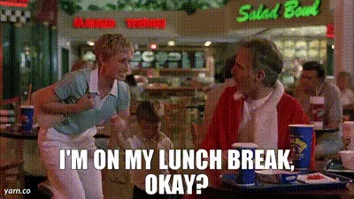 A still from the movie 'Grease' shows a young man in a light blue shirt and white pants repeatedly asking a man in a red…