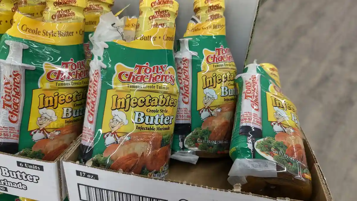 Several bottles of Tony Chachere's 'Injectables Creole Style Butter' are displayed in a store, each labeled as an…