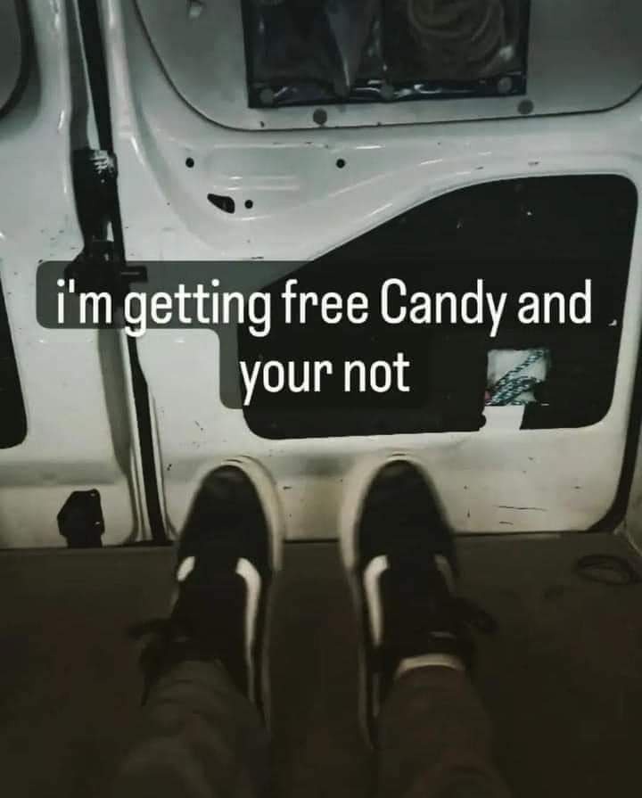 A first-person view from inside a vehicle with the door open, showing a person's feet in black and white sneakers. The…