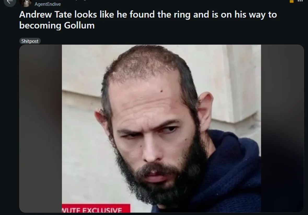 A close-up photo of Andrew Tate, who has a receding hairline, a full beard, and a very intense, focused expression with…