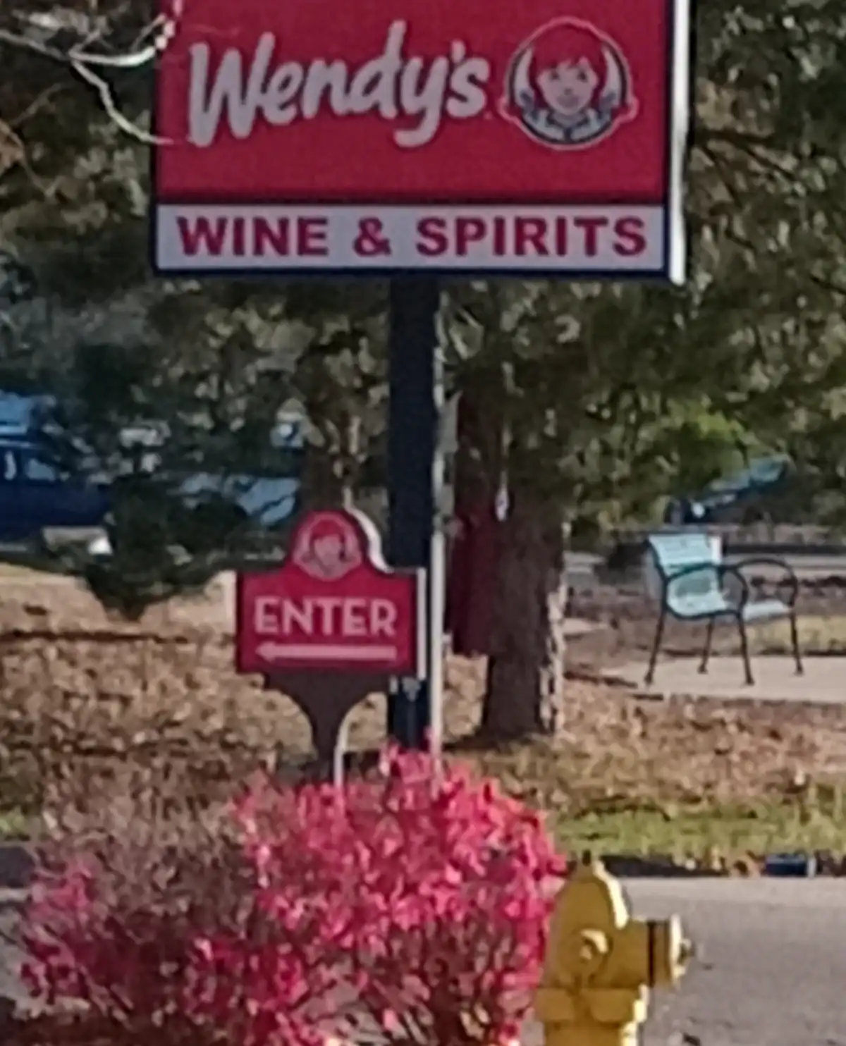 A blurry outdoor photo shows a Wendy's restaurant sign with 'WINE & SPIRITS' written below the logo. A smaller red sign…