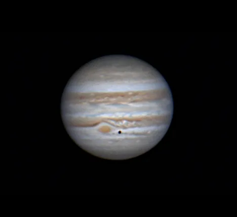 A blurry image of the planet Jupiter, showing its characteristic swirling bands of beige and white clouds against a black…