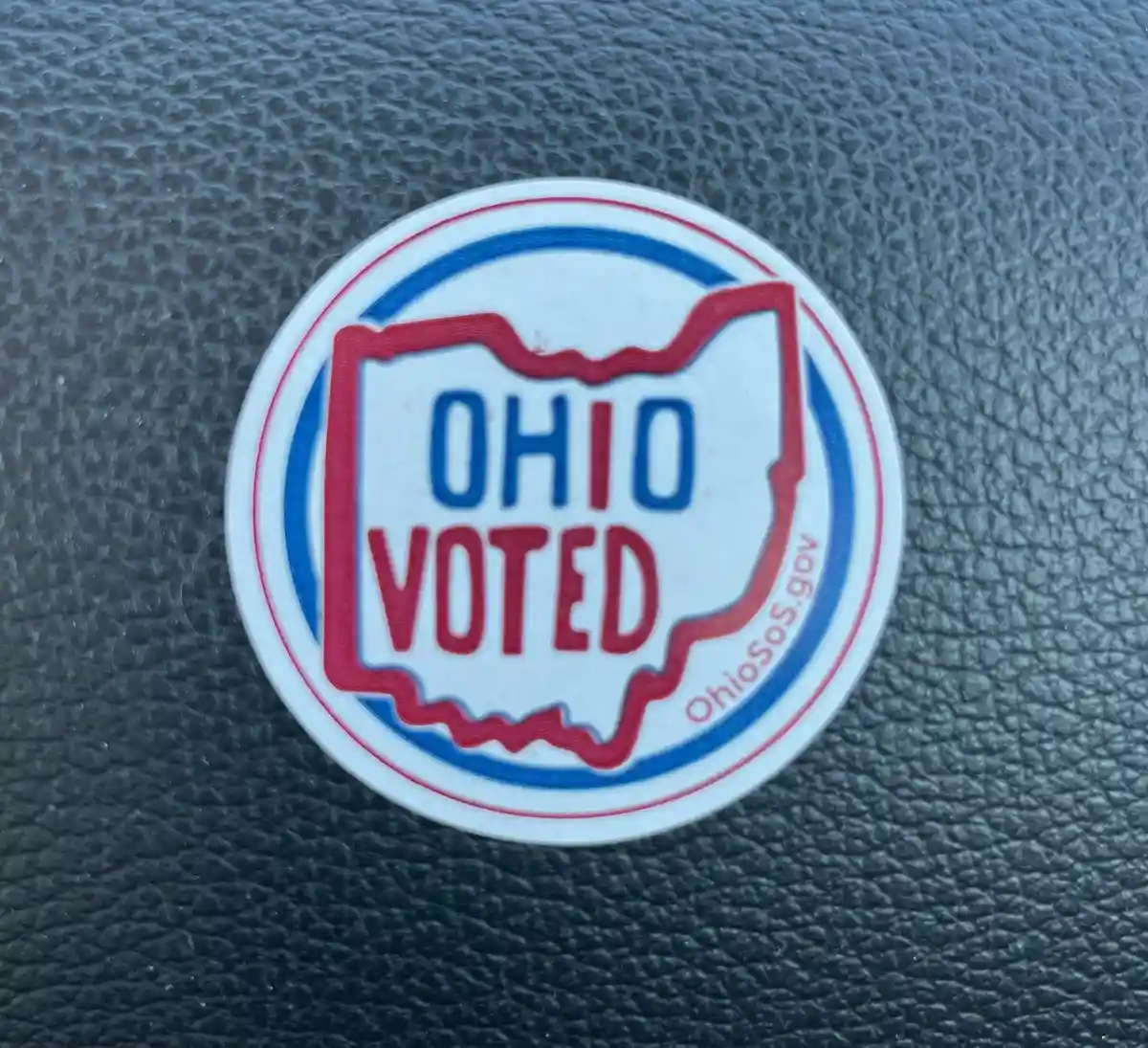 A circular white sticker with red and blue borders features the outline of the state of Ohio in red, with the words 'OHIO'…