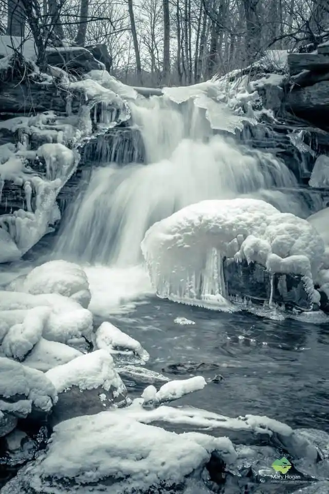 A black-and-white photograph of a frozen waterfall with snow-covered rocks and icicles, overlaid with the text 'i'm not…