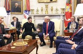 A photo of Donald Trump seated at a large wooden table in the Oval Office, surrounded by several other men in suits. He is…