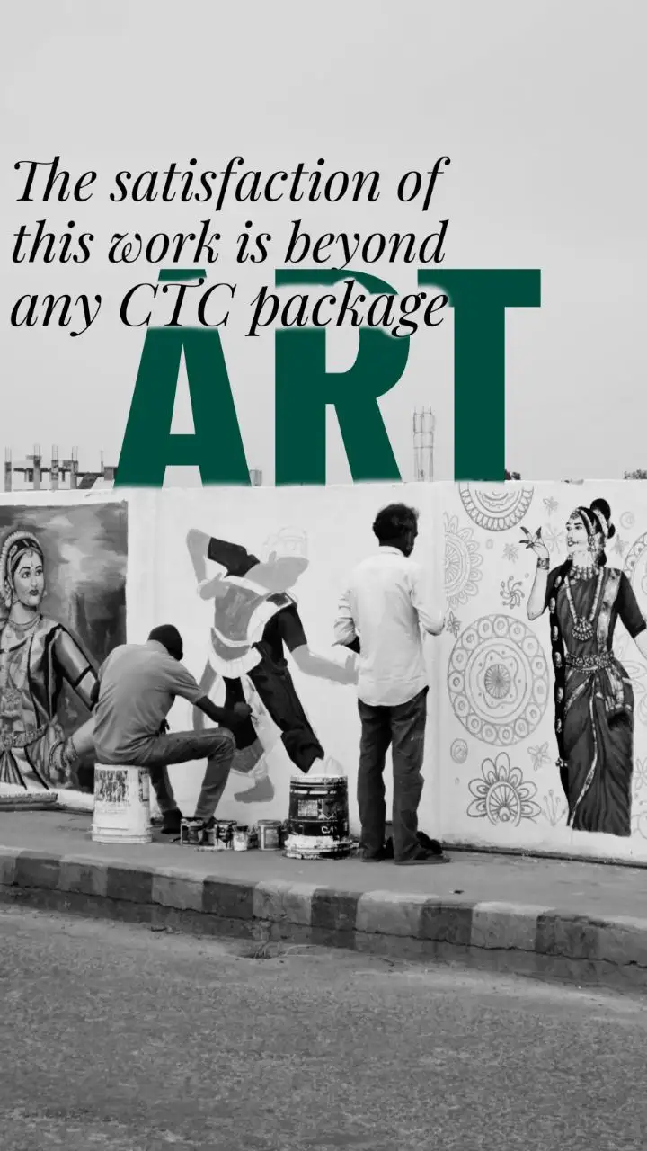 Two men paint elaborate murals on a white wall, one kneeling on a bucket, the other standing. The wall features detailed…