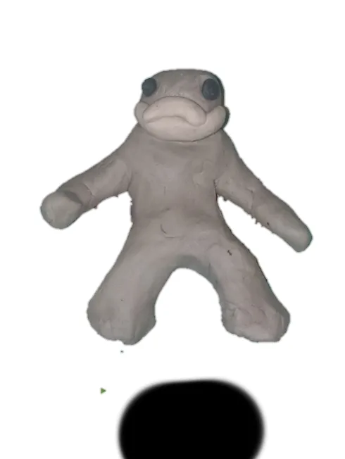 A gray, crudely sculpted clay figure with large black eyes and a wide, downturned mouth, resembling a simplistic humanoid or…