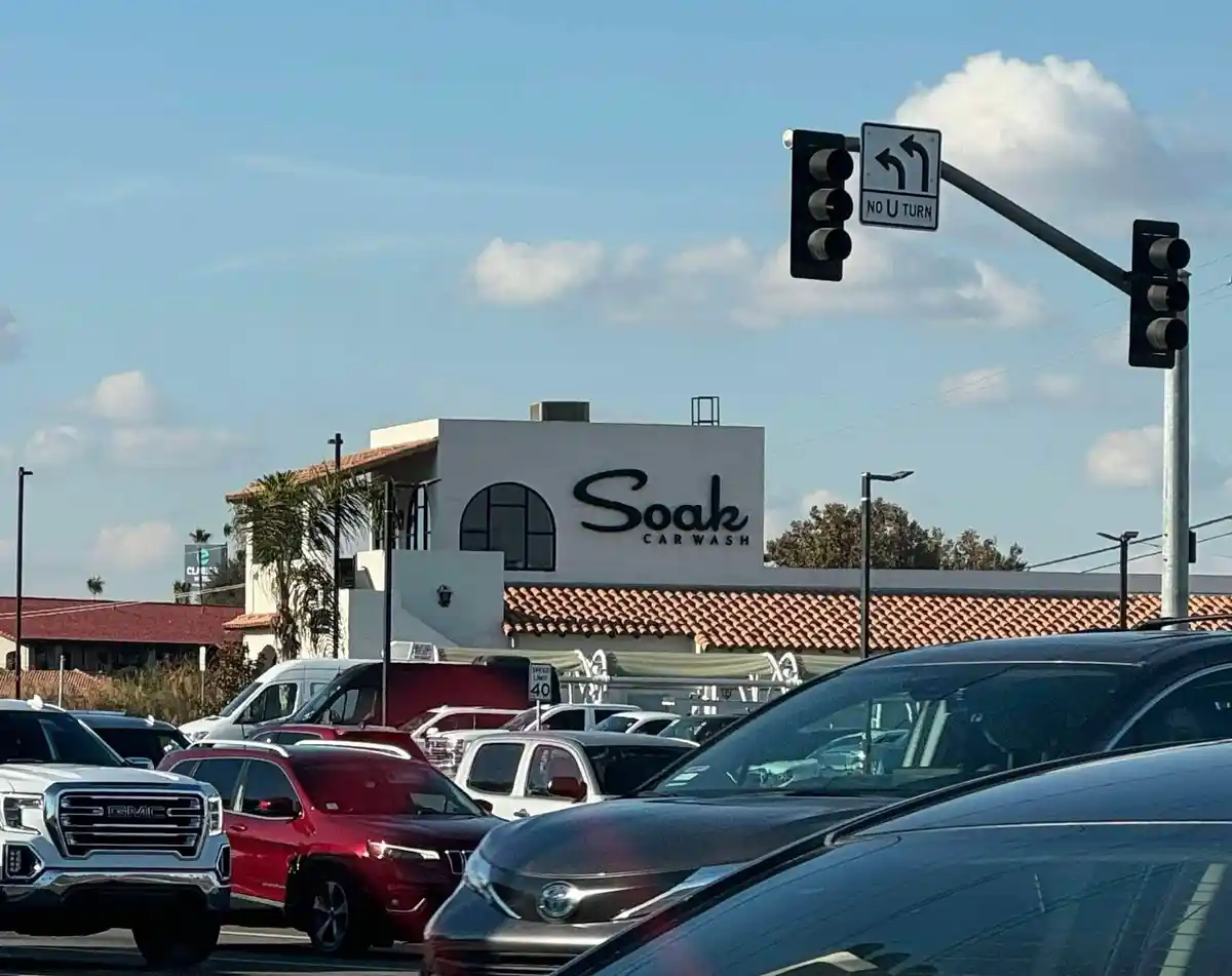 A street view shows a busy road with multiple cars, including a red SUV and a silver Toyota, in front of a white building…