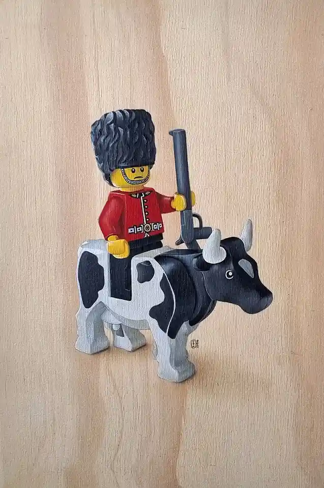 A painted wooden artwork depicts a LEGO British guard minifigure wearing a red coat and tall black bearskin hat, holding a…