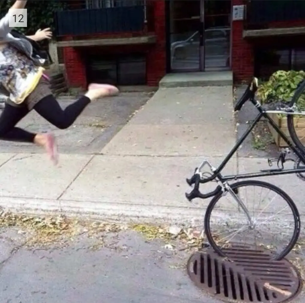 A person is captured mid-air, running away from a bicycle that is stuck with its front wheel on a storm drain cover. The…