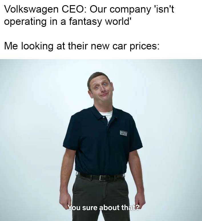 A man in a dark blue polo shirt and grey pants stands against a plain light background, looking upward with a skeptical…
