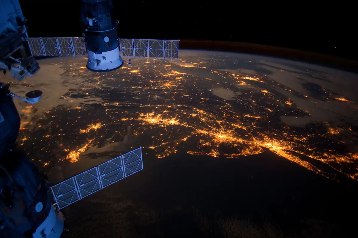A photograph taken from the International Space Station shows Earth at night, with city lights glowing across the planet's…
