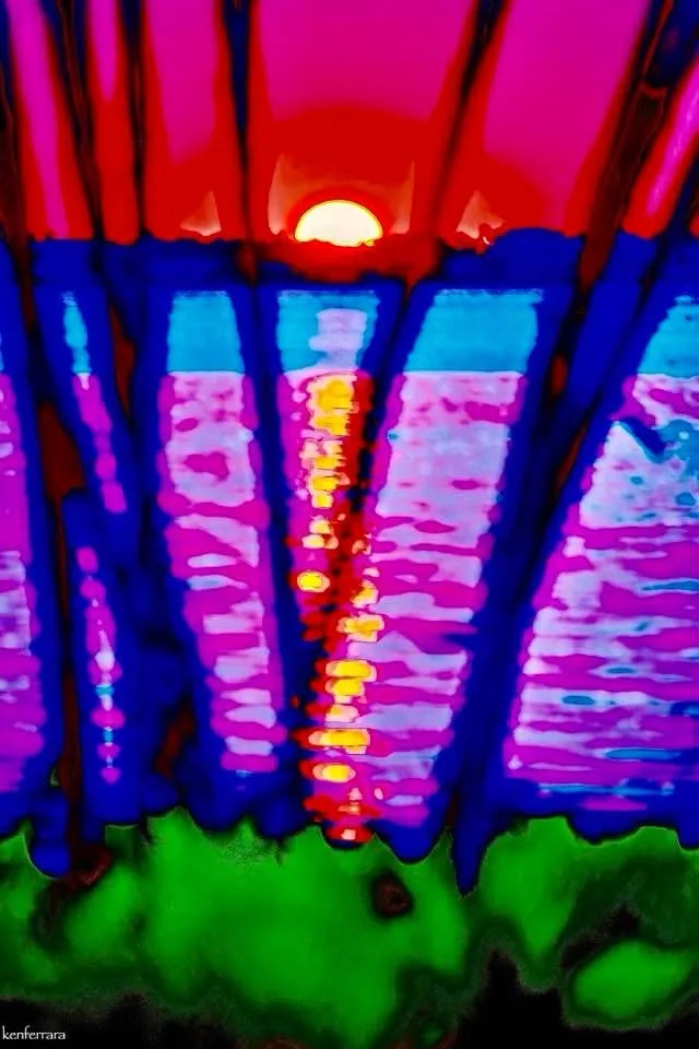 A highly saturated, stylized image shows a sunset with a bright yellow sun over a body of water, framed by vertical…
