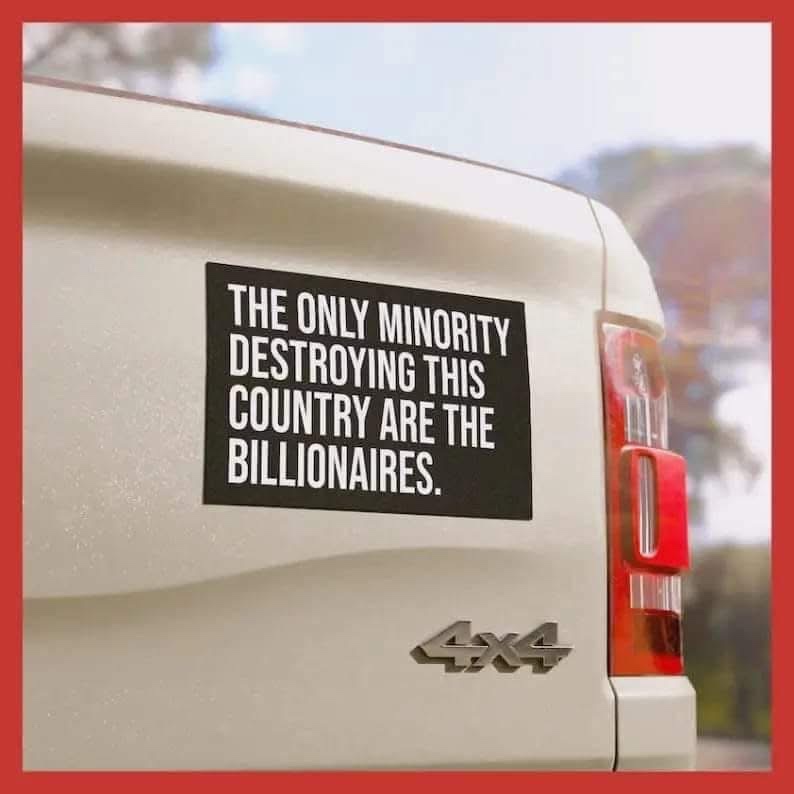 A close-up photo shows a black rectangular sticker on the rear tailgate of a light-colored 4x4 vehicle, with the white text…
