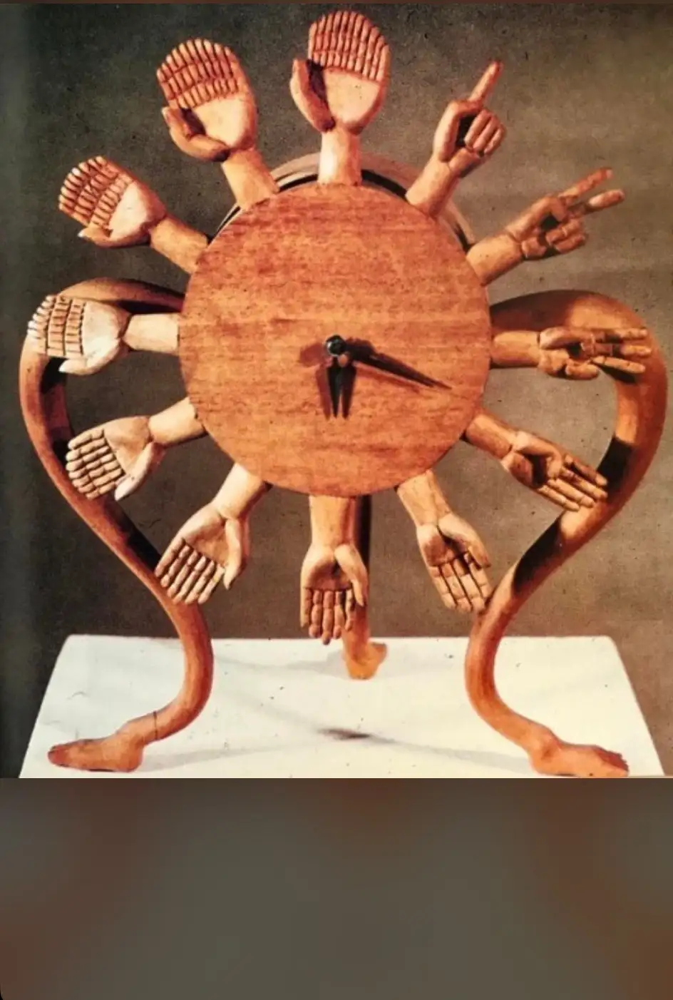 A wooden sculpture resembling a clock with a central circular face and multiple arms extending outward, each ending in a…