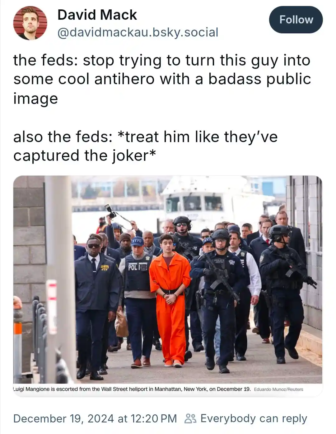 A photo shows Luigi Mangione, a man in an orange jumpsuit, being escorted by numerous heavily armed NYPD officers in…
