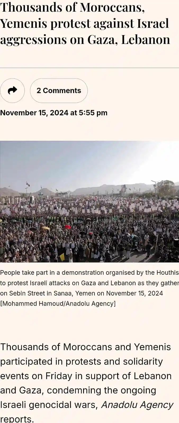 The image shows a large crowd of protesters gathered in a city street, holding signs and banners, with mountains visible in…