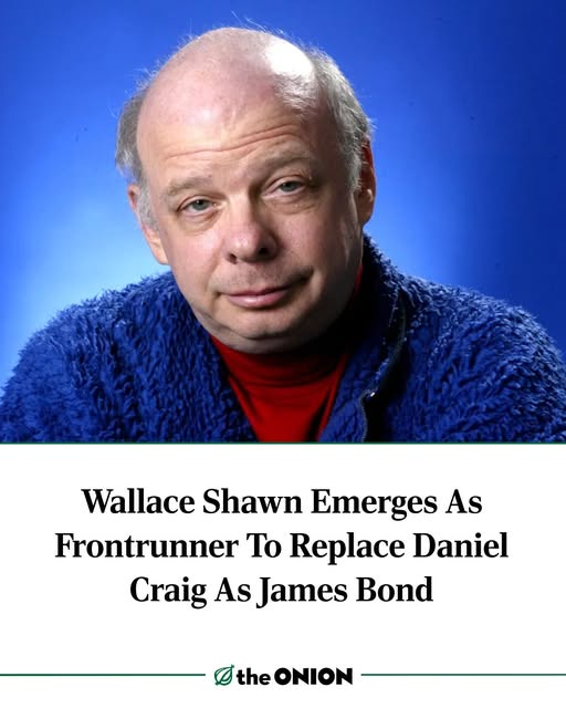 A headshot of actor Wallace Shawn against a blue background, wearing a blue fuzzy jacket over a red turtleneck. Below the…