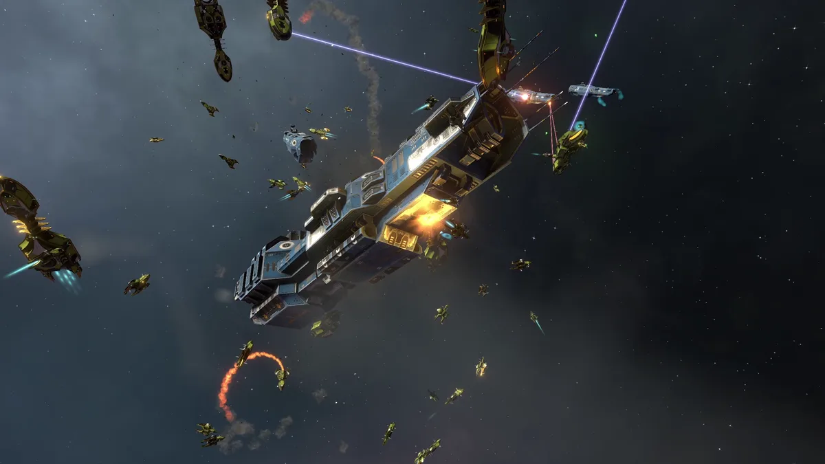 A screenshot from a space battle video game shows a large blue spaceship under heavy attack by numerous smaller green ships…