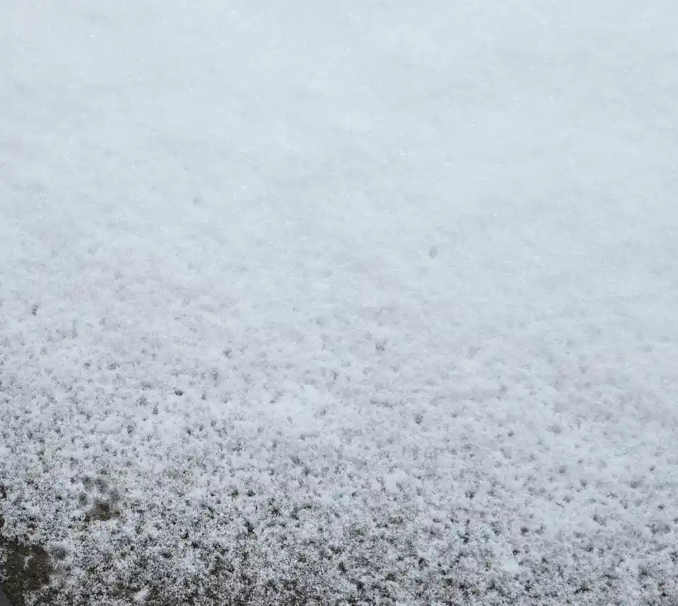 A close-up photo shows a textured surface of fresh snow covering dark ground, with the word 'snow' overlaid in white text…