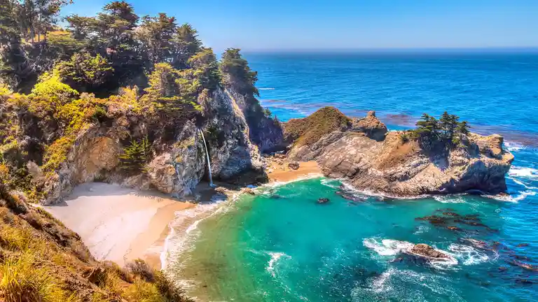 The McWay Falls stream gently flows into the sea along California's scenic Route 1. Year-round, visitors enjoy this Big Sur…