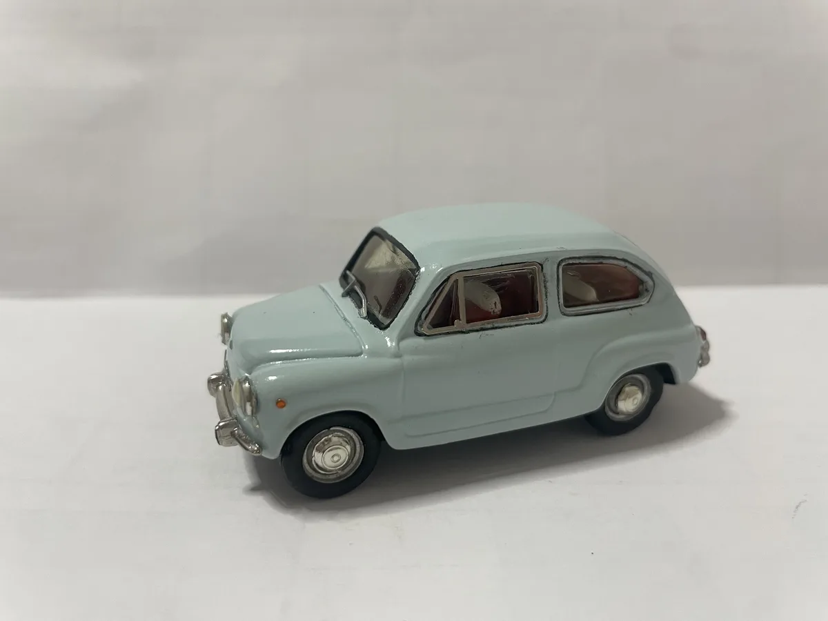 A light blue vintage toy car, resembling a Fiat 500, is photographed against a plain white background. The car has silver…