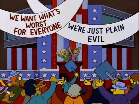A three-panel comic strip from The Simpsons shows a crowd of cartoon characters at a rally with banners reading 'WE WANT…