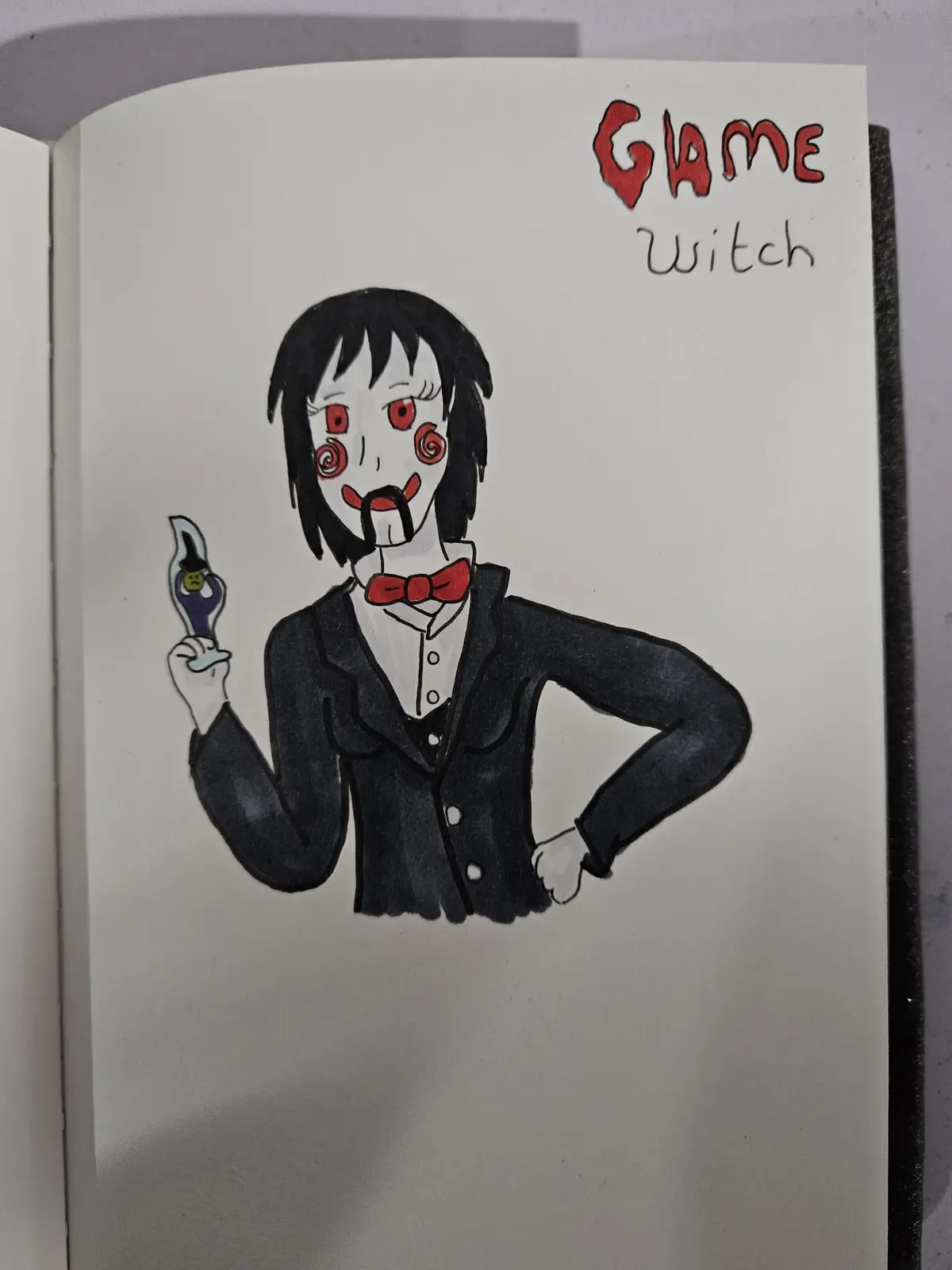 A hand-drawn illustration in a notebook shows a character with black hair, red eyes, and red spiral marks on cheeks, wearing…